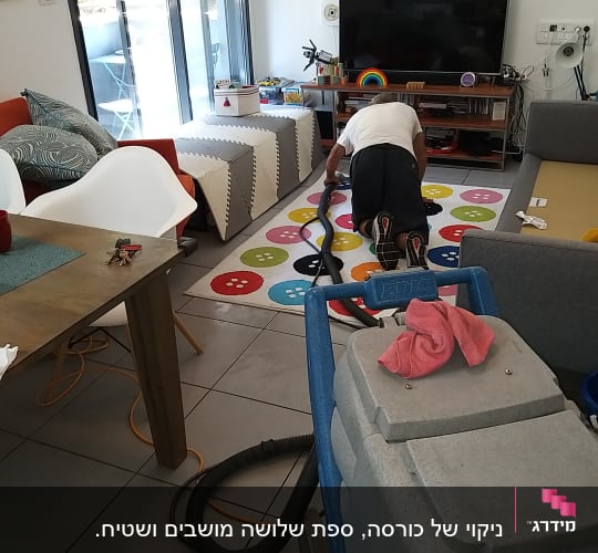 אדם מנקה שטיח עם שואב אבק מקצועי